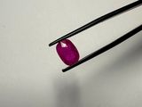 a close up of a pair of tweet tongs holding a ruby stone
