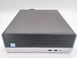 the front of a silver hp desktop computer sitting on top of a white surface