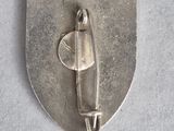 a silver metal badge with a plane on it