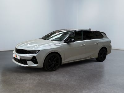 Une voiture argentée est garée dans une pièce blanche au sol noir.