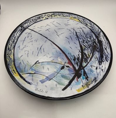 a plate with a painting on it sitting on a table
