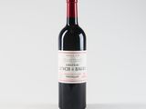 a bottle of red wine sitting on top of a white table
