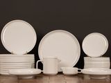 several white plates and cups are stacked on a wooden table