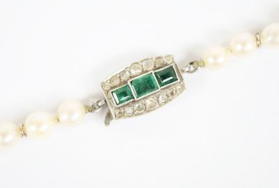 un gros plan sur un collier orné de perles et d'émeraudes