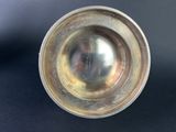 an antique silver plate with a metal rim on a black surface