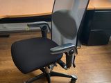 a black office chair sitting in front of a computer desk