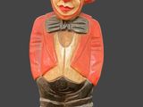 a wooden statue of a clown with a hat and tie