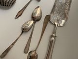 many silver spoons and spoon knives on the table