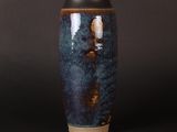 a blue vase sitting on a table with a black background