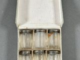 six bocaux en verre dans une boîte blanche posée sur une surface grise