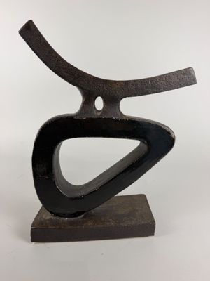 sculpture représentant un objet en métal noir incurvé posé sur un socle en bois