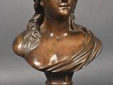 un buste en bronze représentant une femme portant un chapeau sur la tête