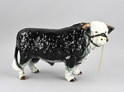 une figurine de vache en noir et blanc avec une corde dans la bouche