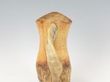 a wooden vase with a bird on it on a white surface