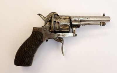 un vieux revolver avec une poignée en bois sur une surface blanche