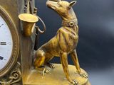 a gold clock with a statue of a woman and a dog on it