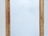 a gold framed mirror on the wall next to a white wall