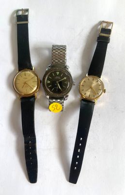 three watches are sitting next to each other on a white surface