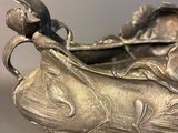 a silver fish shaped bowl with a lady on it