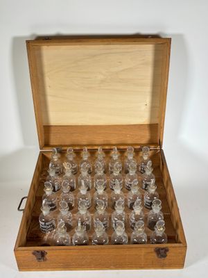 une boîte en bois remplie de bouteilles en verre posée sur une surface blanche