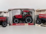 three red toy tractors in boxes on a white surface