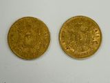 two gold coins sitting next to each other on a white surface