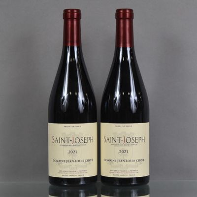 two bottles of red wine sit on a table in front of a gray background