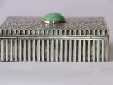 an antique silver box with a green stone on top