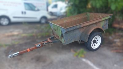 une petite remorque à laquelle est attelée une autre remorque, dans un parking