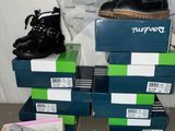 Plusieurs paires de chaussures sont empilées sur des cartons posés sur une table