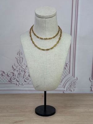 un collier à chaîne en or sur un mannequin posé sur une table en bois