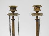 pair of antique brass candlesticks with chains on a white background