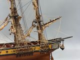 wooden model of a tall sailing ship on a white surface