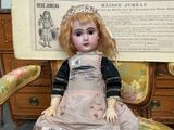 a doll that is sitting on a chair in front of a poster