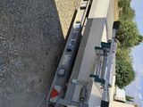 a flat bed trailer parked in a gravel lot