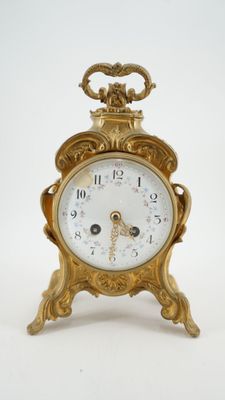 une horloge en or surmontée d'une couronne