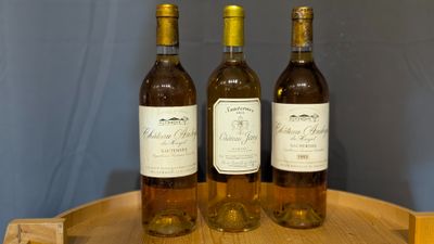 three bottles of wine sitting on top of a wooden barrel
