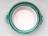 a green and white bowl with a handle on a table