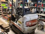 une petite pelleteuse garée dans un garage