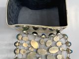gold and black metal bracelet with a black glass container on a white surface