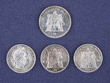 four silver coins of different sizes and shapes on a blue surface