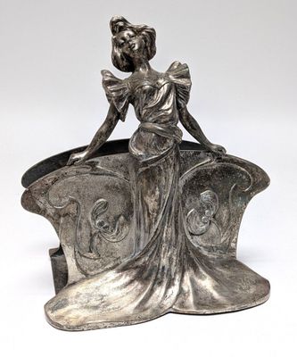 a silver statue of a woman sitting on top of a chair