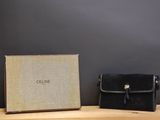 La pochette noire se trouve à côté de la boîte, sur la table en bois.