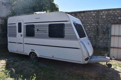 une petite caravane blanche garée dans un jardin