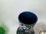 a blue vase sitting next to a green vase on a table