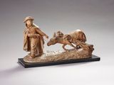 statue représentant un homme avec un cheval tirant une charrette sur laquelle se trouve un autre homme