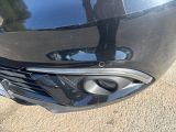 a close up of a car ' s front bumper with a person standing in the background
