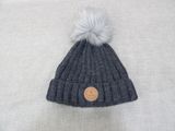 a gray hat with a white pom on top of it