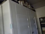 un réfrigérateur au milieu d'une pièce, avec une étagère au-dessus