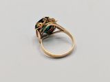 a close up of a gold ring with a green stone